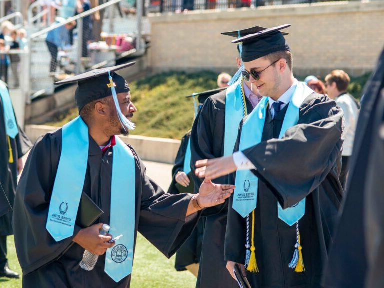 两位伊利诺伊大学毕业生在毕业典礼上握手